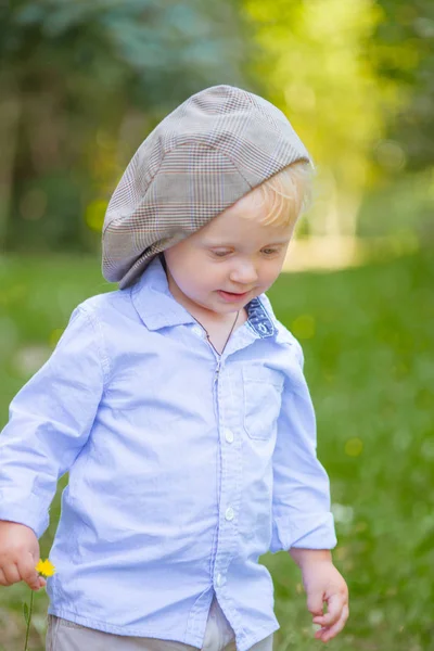 花が畑で夏にキャップと青シャツでブロンドの髪を持った少年 — ストック写真
