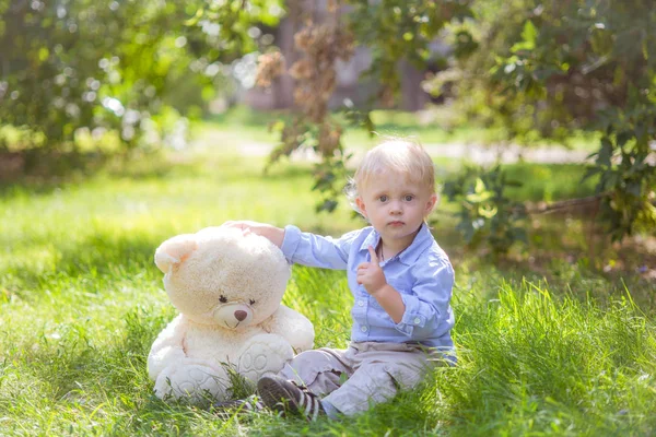 Mały Chłopiec Blond Włosy Zabawa Misiem Zielonej Trawie Letni Dzień — Zdjęcie stockowe