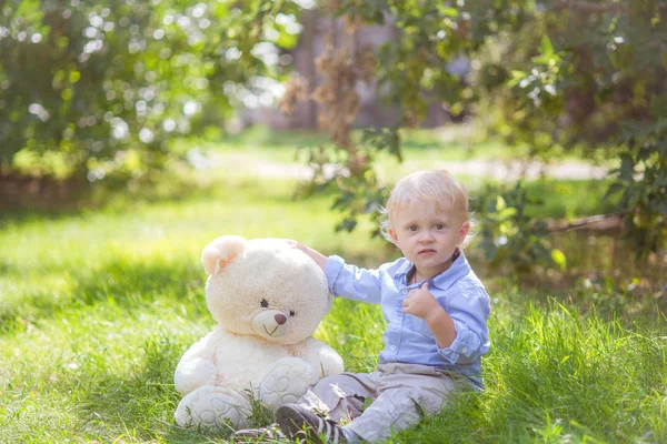 Mały Chłopiec Blond Włosy Zabawa Misiem Zielonej Trawie Letni Dzień — Zdjęcie stockowe