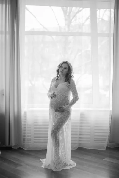 年轻美丽的孕妇肚皮的孕妇 可爱的怀孕的肚子 美丽的孕妇金发女郎在白色蕾丝佩格诺尔 女孩在白色内衣 — 图库照片