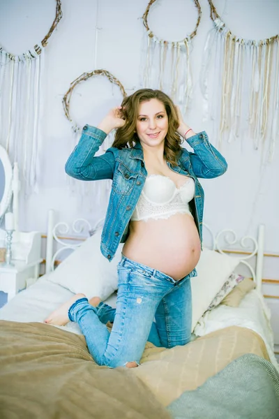 青いジーンズの美しい妊婦はベッドの上にあります 幸せな母性 健康的なライフスタイルの概念 — ストック写真