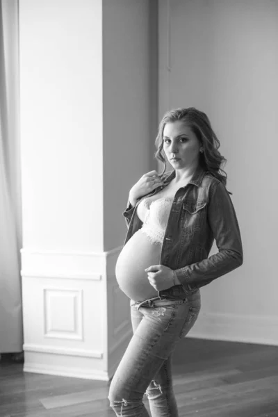 美丽的孕妇穿蓝色牛仔裤和牛仔夹克 幸福母亲的概念 健康的生活方式 — 图库照片
