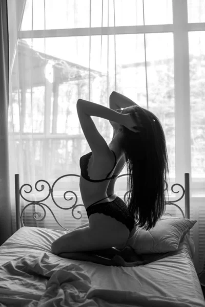 一个迷人的性感的女人的肖像与深色长发内衣躺在床上 — 图库照片