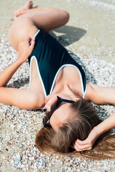 수영복과 선글라스에 머리를 아름다운 소녀는 화창한 바다에서 해변에서 휴식을 취합니다 — 스톡 사진