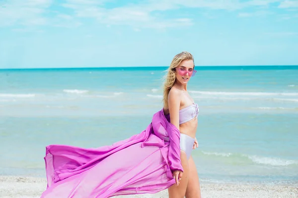 ピンクの水着とサングラスをかけた若い女性は 晴れた暑い日に海のビーチでリラックス — ストック写真