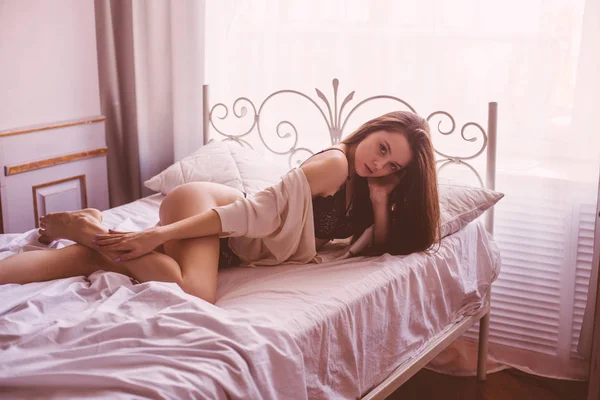 ベッドの上に横たわっている黒いレースのランジェリーで暗い長い髪を持つ魅力的なセクシーな女性の肖像画 — ストック写真