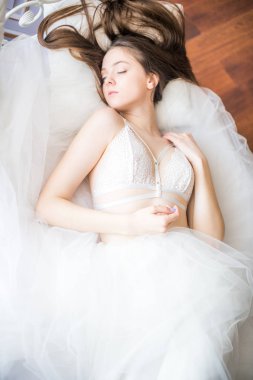 Siyah uzun saçlı sabah evde beyaz bir yatak beyaz dantel büstiyer ve elbise ile genç güzel gelin