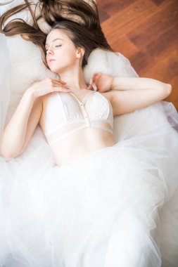 Siyah uzun saçlı sabah evde beyaz bir yatak beyaz dantel büstiyer ve elbise ile genç güzel gelin