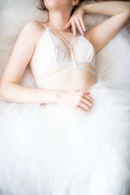 Siyah uzun saçlı sabah evde beyaz bir yatak beyaz dantel büstiyer ve elbise ile genç güzel gelin