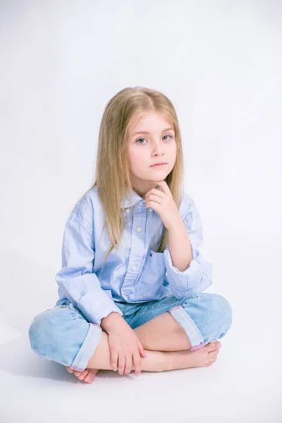 美丽的时尚小女孩与金发在牛仔裤的衣服上的白色背景在工作室 — 图库照片