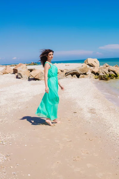 Krásná mladá dívka v dlouhých šatech na pláži — Stock fotografie