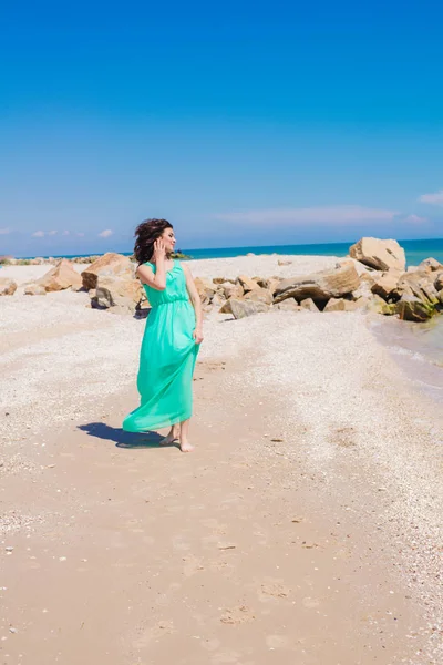 Mooi meisje in een lange jurk op het strand — Stockfoto