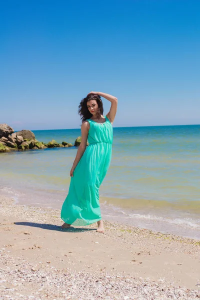 Mooi meisje in een lange jurk op het strand — Stockfoto