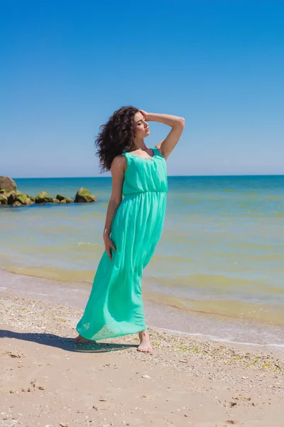 Ung vacker flicka i en lång klänning på stranden — Stockfoto