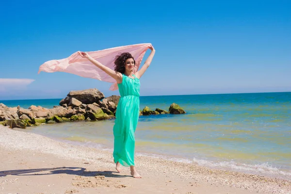 Jong meisje op het strand in de zomer in een mooie jurk met een vliegende sjaal — Stockfoto