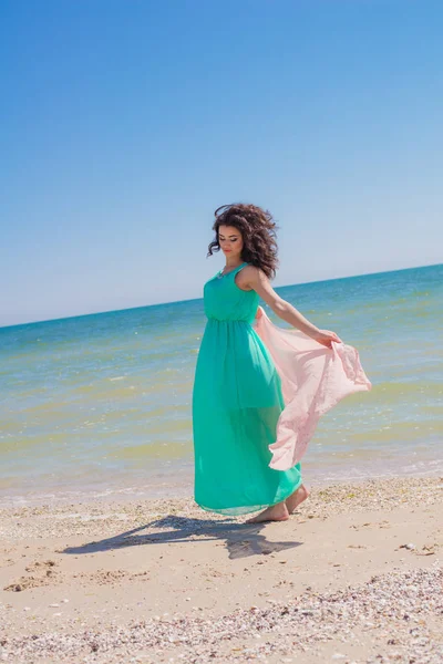 Chica joven en la playa en verano en un hermoso vestido con una bufanda voladora — Foto de Stock