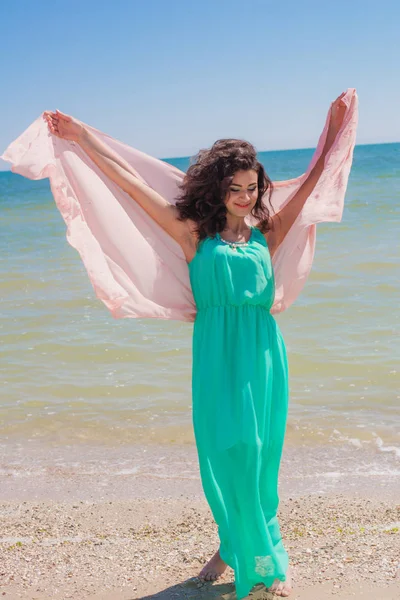 Jong meisje op het strand in de zomer in een mooie jurk met een vliegende sjaal — Stockfoto