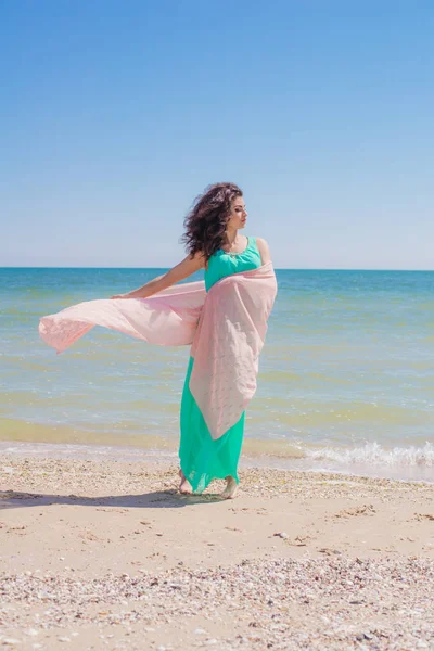 Молодая девушка на пляже летом в красивом платье с летающим шарфом — стоковое фото