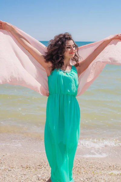 Young girl on the beach in summer in a beautiful dress with a flying scarf — Stock Photo, Image