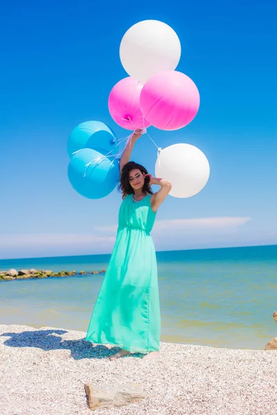 Девушка на пляже с цветными воздушными шарами — стоковое фото