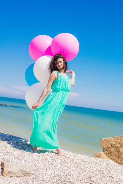 Menina bonita na praia com balões coloridos — Fotografia de Stock