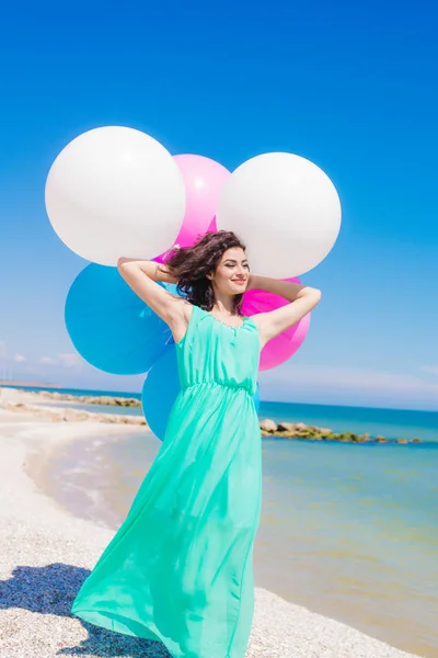 Menina bonita na praia com balões coloridos — Fotografia de Stock