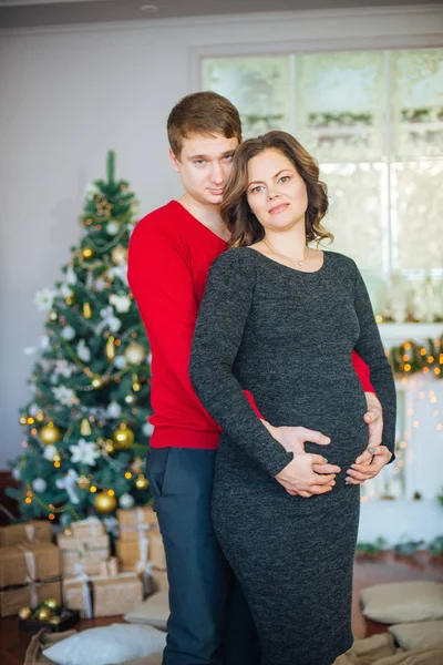 Schöne Schwangere Verliebte Pärchen Vor Dem Hintergrund Eines Weihnachtsbaums Die — Stockfoto