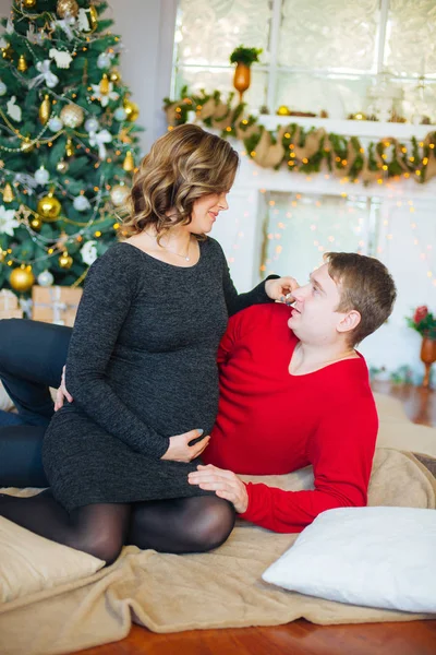 Schöne Schwangere Verliebte Pärchen Vor Dem Hintergrund Eines Weihnachtsbaums Die — Stockfoto