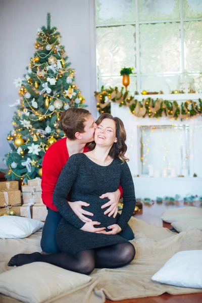 Schöne Schwangere Verliebte Pärchen Vor Dem Hintergrund Eines Weihnachtsbaums Die — Stockfoto