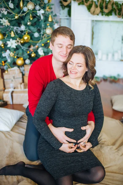 Schöne Schwangere Verliebte Pärchen Vor Dem Hintergrund Eines Weihnachtsbaums Die — Stockfoto