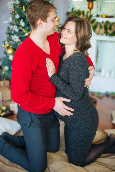 Schöne Schwangere Verliebte Pärchen Vor Dem Hintergrund Eines Weihnachtsbaums Die — Stockfoto