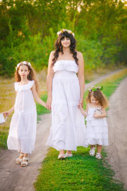 Nehir kıyısında gün batımında bir yaz tarlasında eğlenen beyaz elbiseli kızları ile genç anne