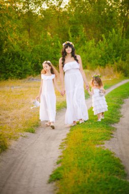 Nehir kıyısında gün batımında bir yaz tarlasında eğlenen beyaz elbiseli kızları ile genç anne