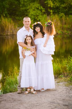 Mutlu ebeveynler ve çocuklar gün batımında bir buğday tarlası ve nehir yaz açık havada eğlenmek