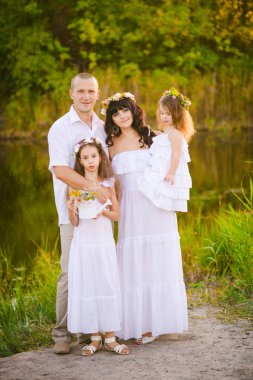 Mutlu ebeveynler ve çocuklar gün batımında bir buğday tarlası ve nehir yaz açık havada eğlenmek