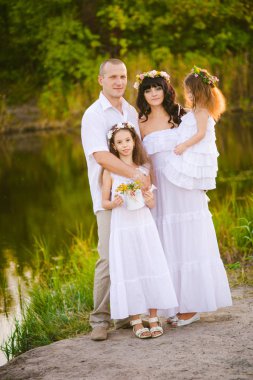 Mutlu ebeveynler ve çocuklar gün batımında bir buğday tarlası ve nehir yaz açık havada eğlenmek