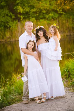 Mutlu ebeveynler ve çocuklar gün batımında bir buğday tarlası ve nehir yaz açık havada eğlenmek