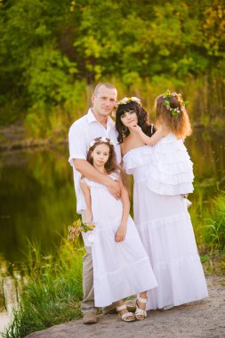 Mutlu ebeveynler ve çocuklar gün batımında bir buğday tarlası ve nehir yaz açık havada eğlenmek