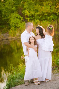 Mutlu ebeveynler ve çocuklar gün batımında bir buğday tarlası ve nehir yaz açık havada eğlenmek