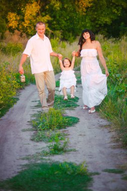 Mutlu ebeveynler ve gün batımında bir buğday tarlası ve nehir yaz açık havada eğlenmek küçük daugther