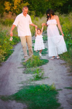 Mutlu ebeveynler ve gün batımında bir buğday tarlası ve nehir yaz açık havada eğlenmek küçük daugther