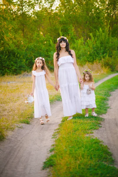 年轻的母亲与她的女儿在白色礼服的乐趣在夏日日落在河边 — 图库照片