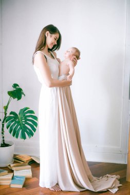 Aile, çocuk ve ebeveyn kavramı - küçük bebek evde ile mutlu gülümseyen genç anne