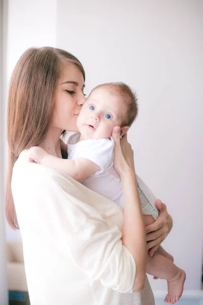 Aile, çocuk ve ebeveyn kavramı - küçük bebek evde ile mutlu gülümseyen genç anne