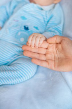 Annenin eli, yatakta evde küçük, sevimli bir bebek tutuyor. Mutlu annelik