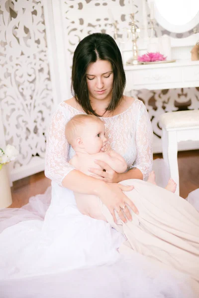 年轻的妈妈 她的怀里抱着一个婴儿在明亮的布道尔卧室 — 图库照片