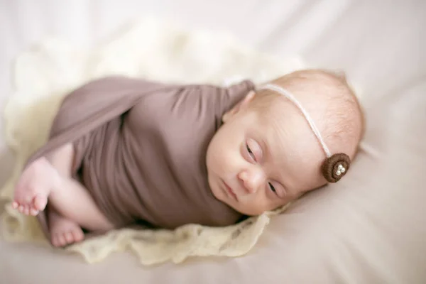 ベッドの上に包まれた茶色の毛布で眠っている新生児 — ストック写真