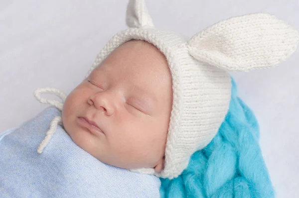 可爱的小宝宝在蓝色毯子和白色帽子与兔子耳朵在床上在家里 — 图库照片