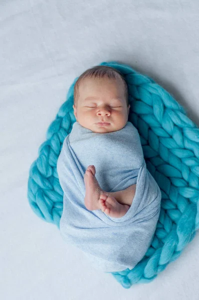 Cute little baby in a blue blanket on the bed at home