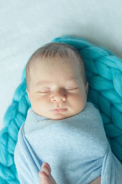 Cute little baby in a blue blanket on the bed at home